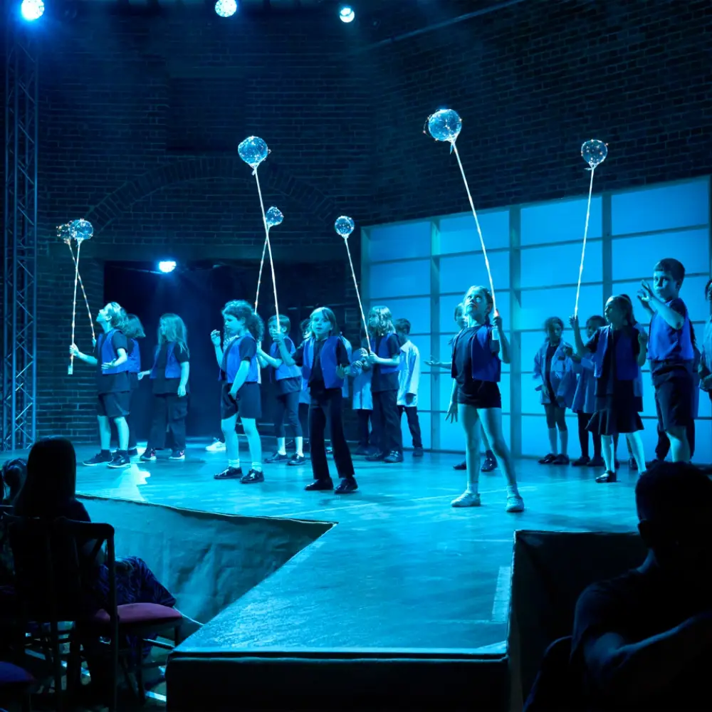 Primary school pupils performing on stage with illuminated props during an IntoOpera production.