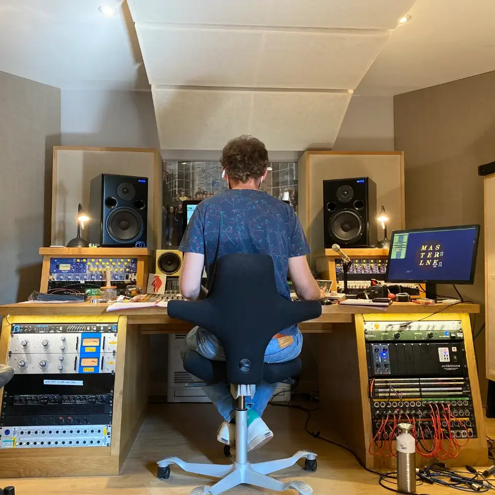 Sound engineer seated at a mixing desk in a professional recording studio.