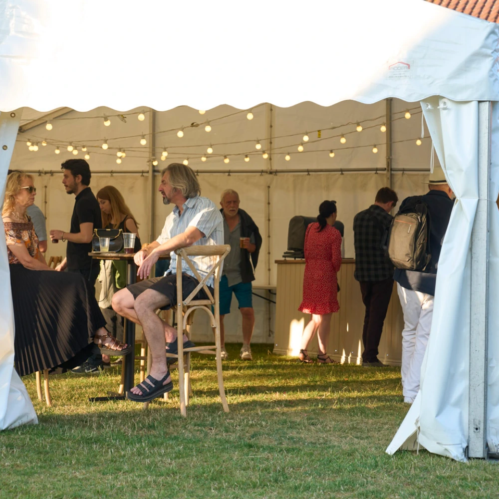 Guests socialising under a marquee at an outdoor IntoOpera event